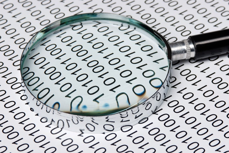 A magnifying glass lies over a sheet of binary code.